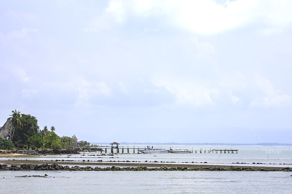 Speed boats moored at the wooden bridge and blue sky in the sea at Laem ngop Pier ,Trat in Thailand.