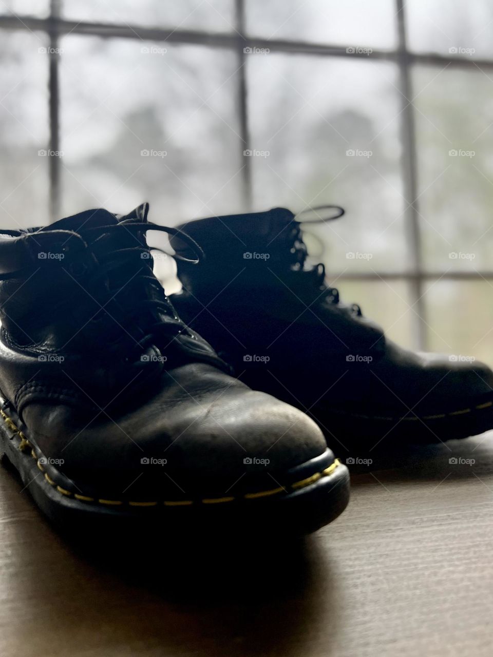 Closeup pair of worn classic Doc Marten boots backlit by window
