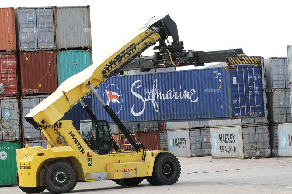 A heavy lifting machine stacking shipping containers in neat rows.