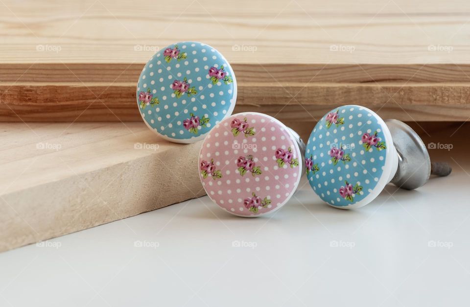 Retro cabinet handles in pinks and blue, displayed with wood