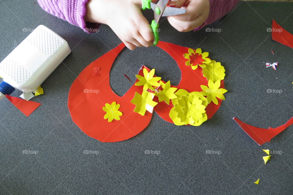 The four-year-old daughter made a gift for her mother: a red heart with yellow flowers is glued on a yellow cardboard. Perfect gift for mom. Happy Valentine's Day!