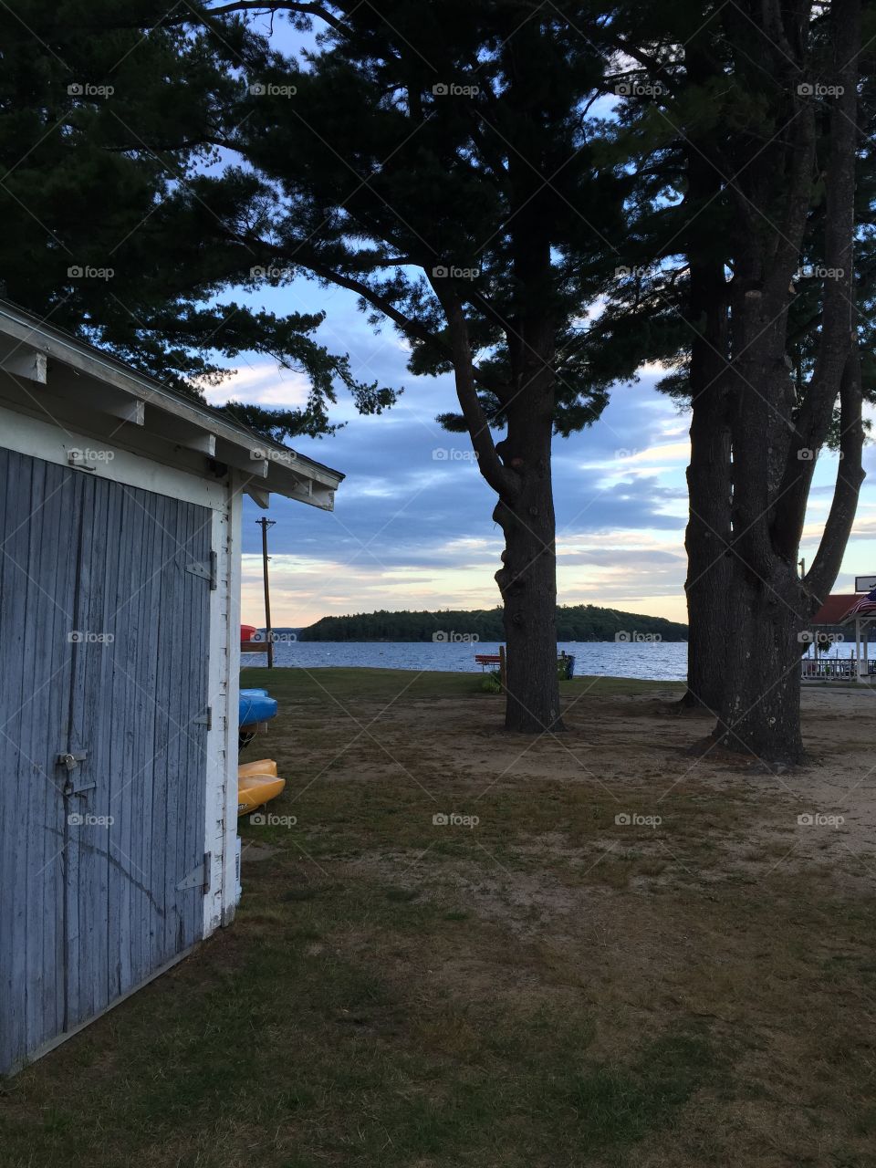 Old weathered wood garage with peeling paint next to lake