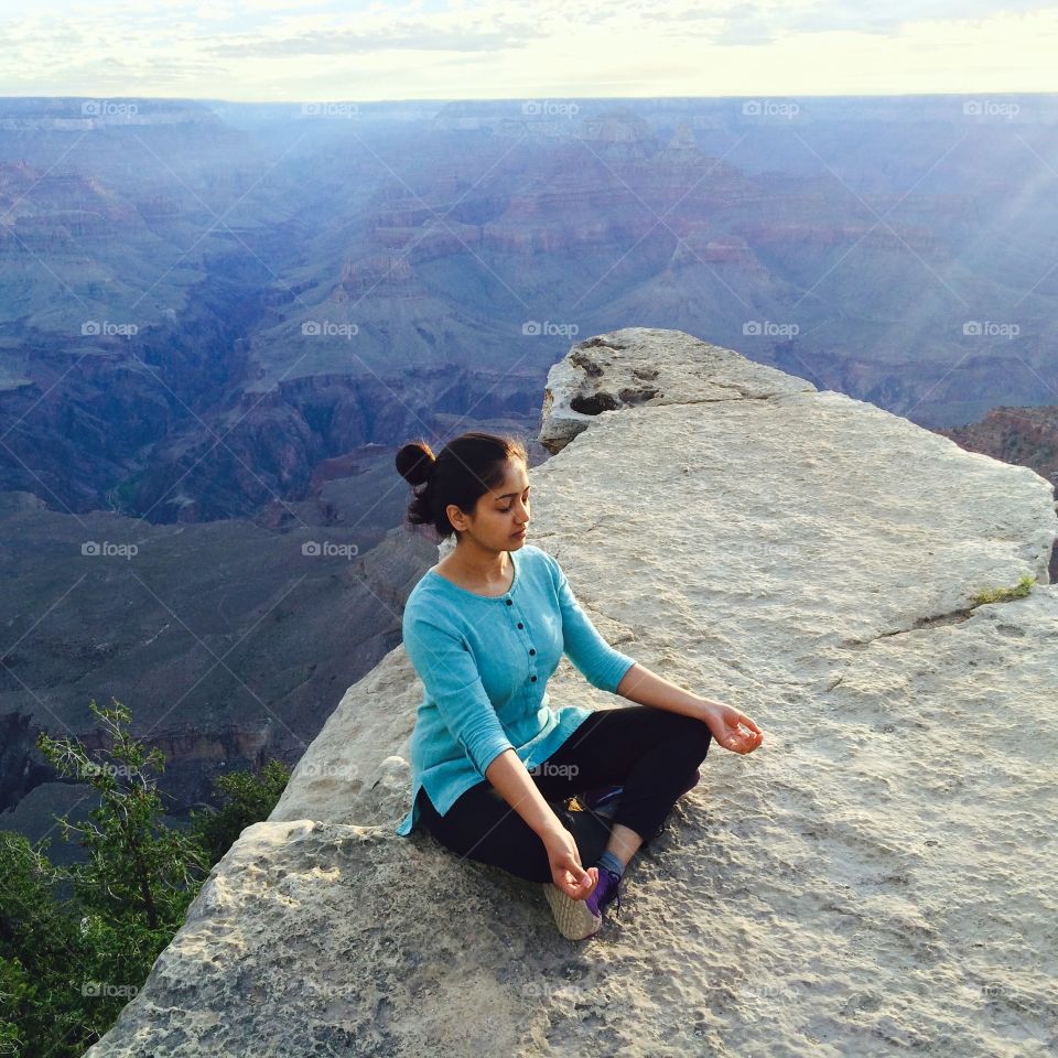 Young woman meditating on rocky mountain