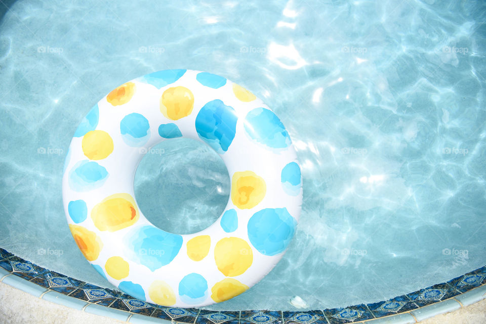 Blue spotted innertube on the clear blue water of a round swimming pool