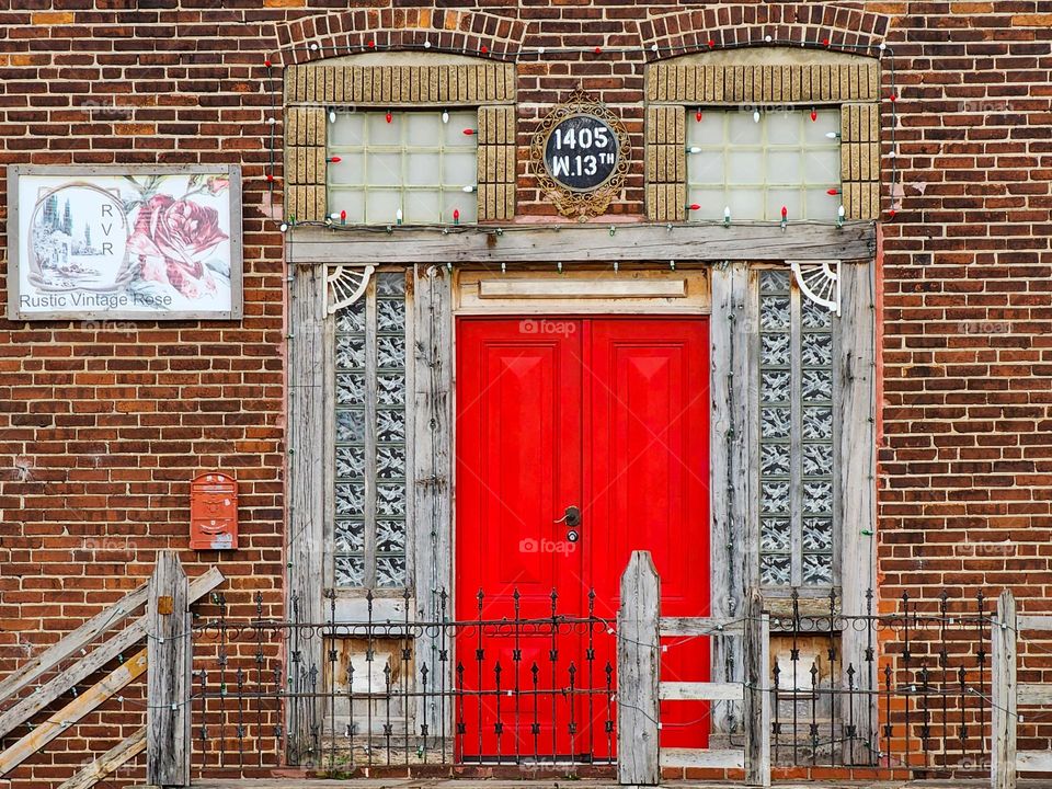 A bright red door adds a beautiful highlight to an otherwise old and bland entrance