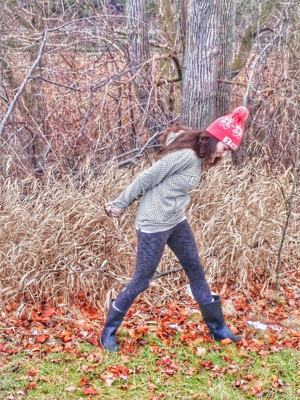 Girl in the forest with big rubber boot and toque in the fall.