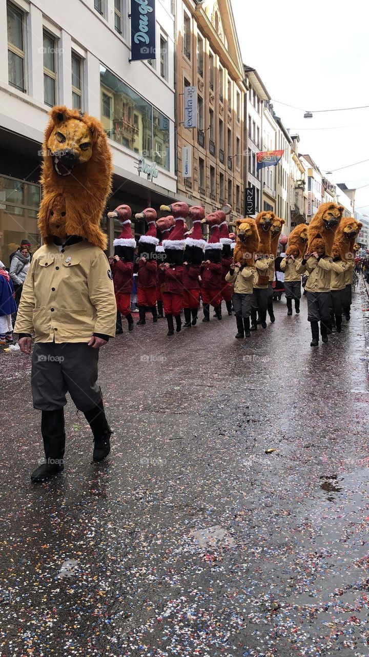 a large crowd of people running in the city among large buildings. a crowd of people in masquerade costumes and masks at a fundamental festival in Switzerland. people in bright costumes on a holiday