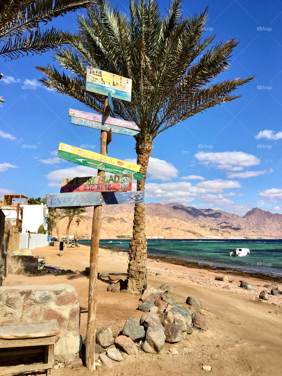 Funny signpost on the beach against the background of palm tree