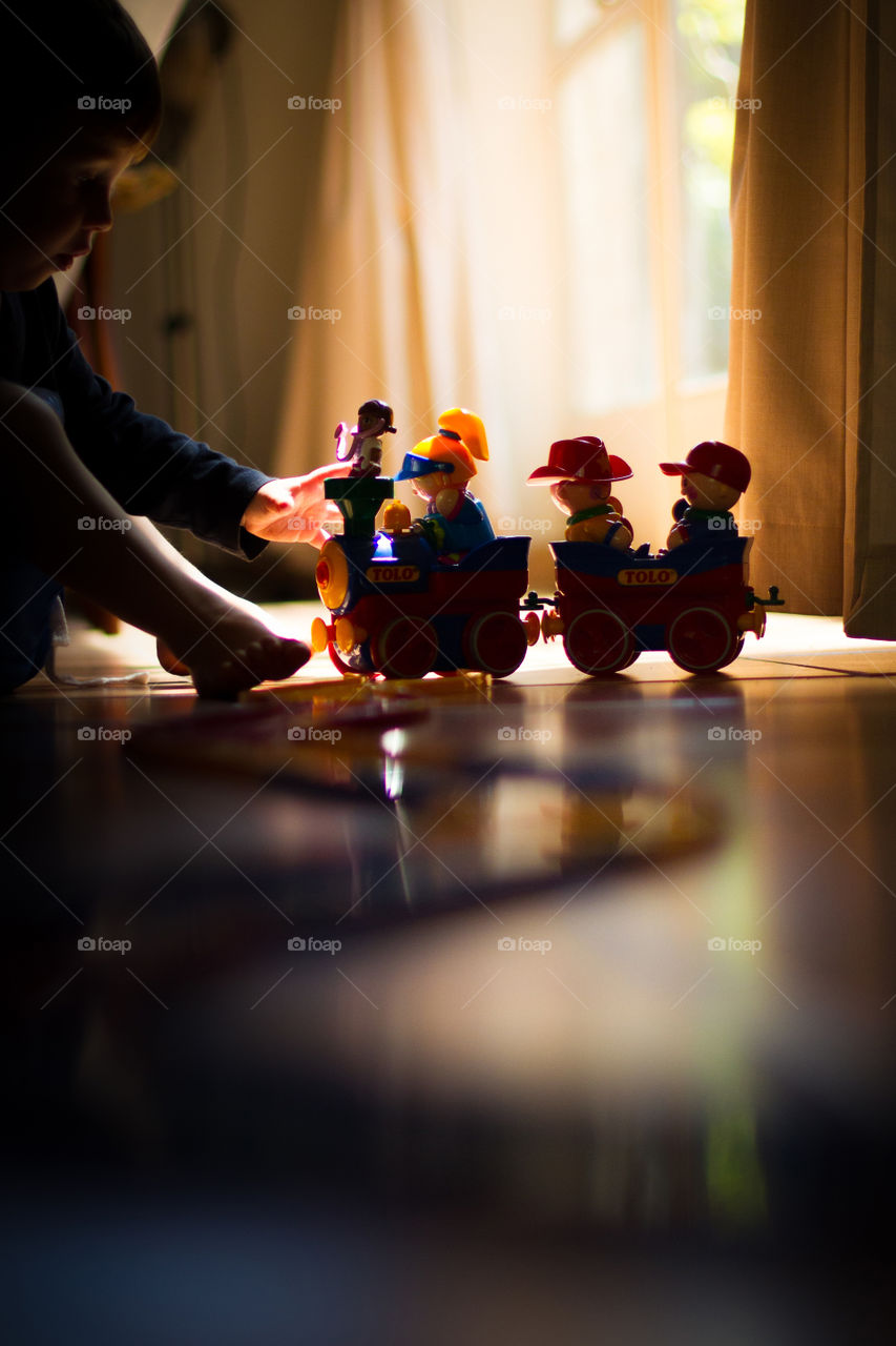 Fun at home - boy playing with toy train and train tracks with interesting window light. Love this natural moment at home of my boy having fun.