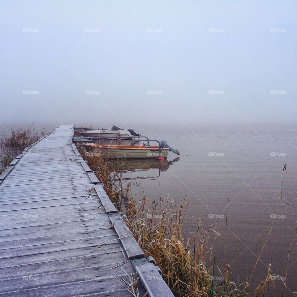 View of boats moored in lake during foggy weather
