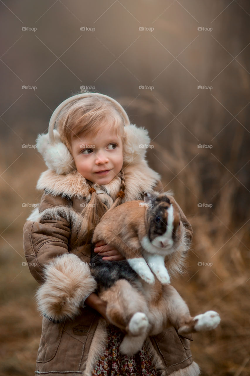 Cute Little girl with bunny in a forest at misty autumn evening 