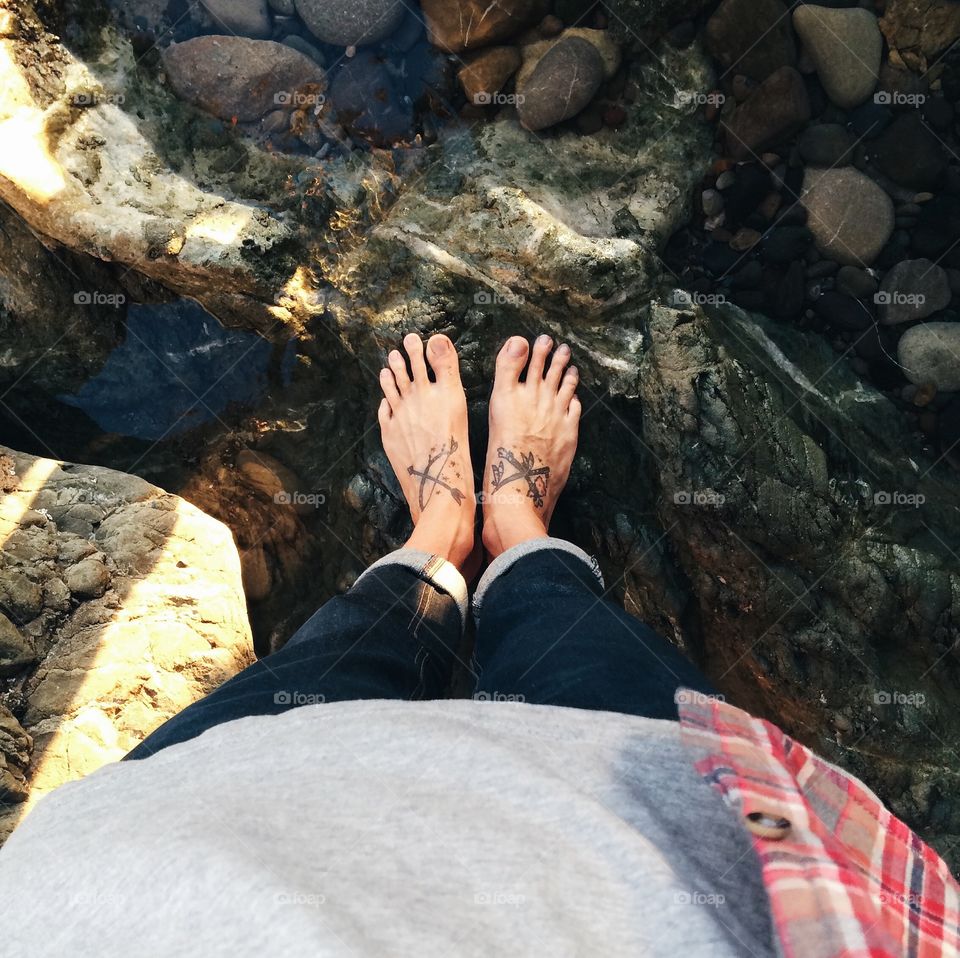 Feet Upon The Rocks. . Tattooed feet on the rocks in the ocean. 