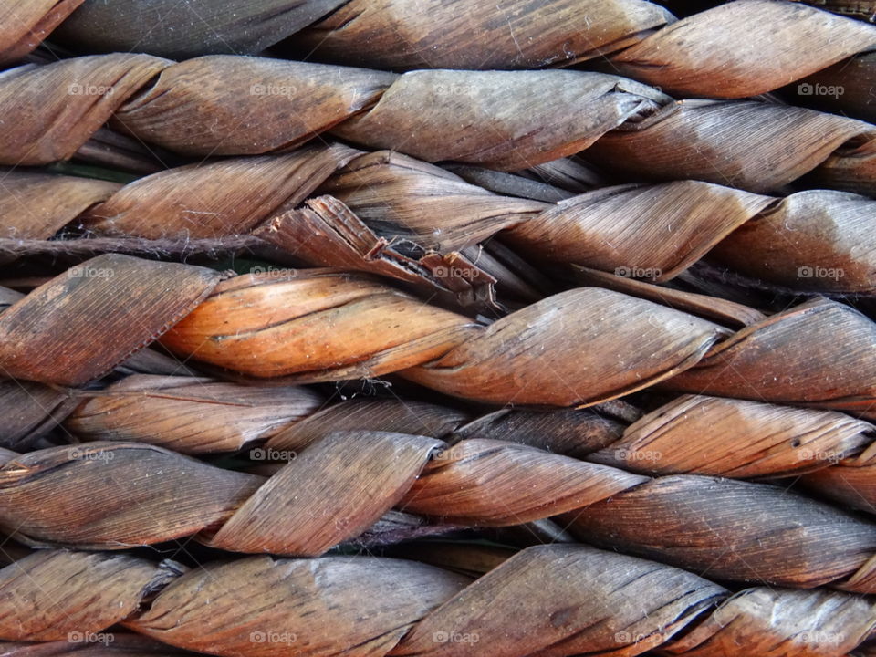 closeup of woven handcrafted plant material, wooden texture and brown