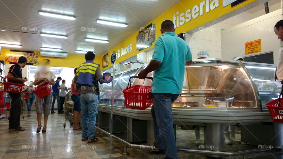 Em Rotisseria e Restaurante, dentro de Supermercado. Pessoas com cestinhas plásticas, aguardando chamada de senhas.