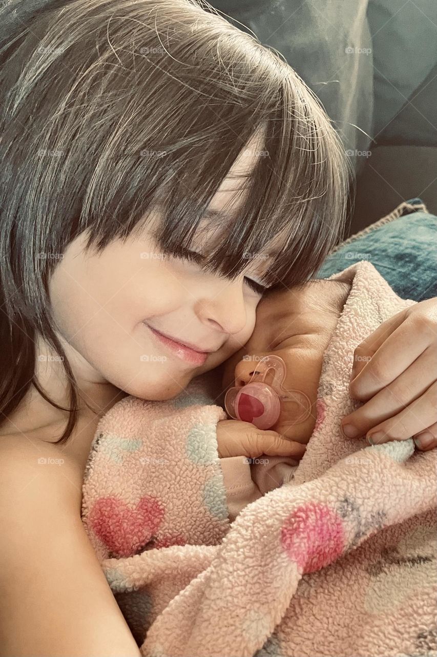 A big brother meets his new baby sister for the first time as he holds her gently