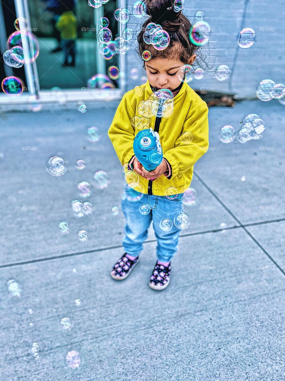 Toddler blowing bubbles outside, bubble circles surround toddler girl outdoors, fun with bubbles outside, using a bubble blower outside, toddler girl makes lots of bubbles, bubbles as an activity for kids, geometric shapes in everyday life