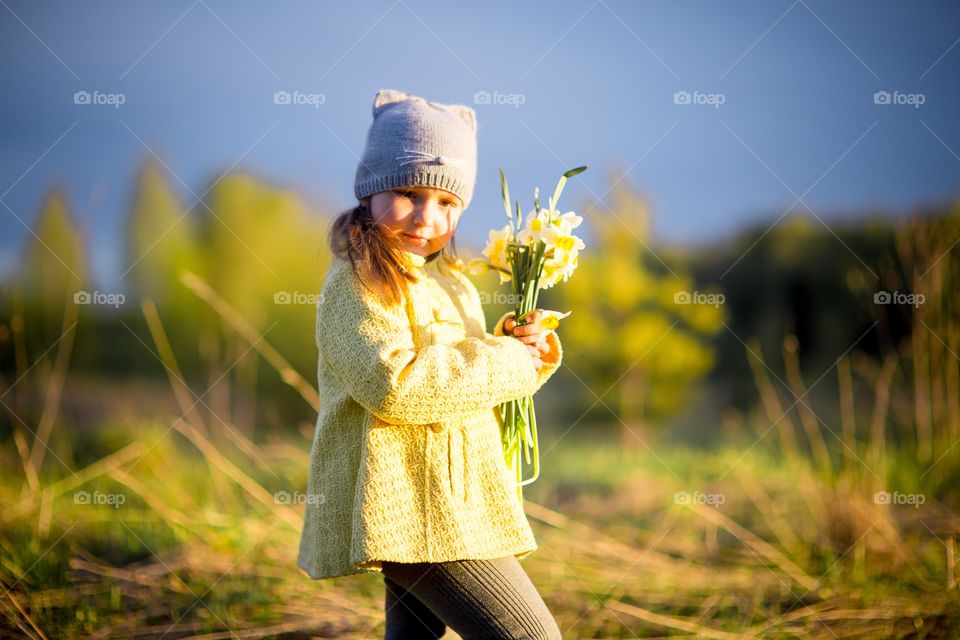 Little girl with narcissus bouquet in spring park