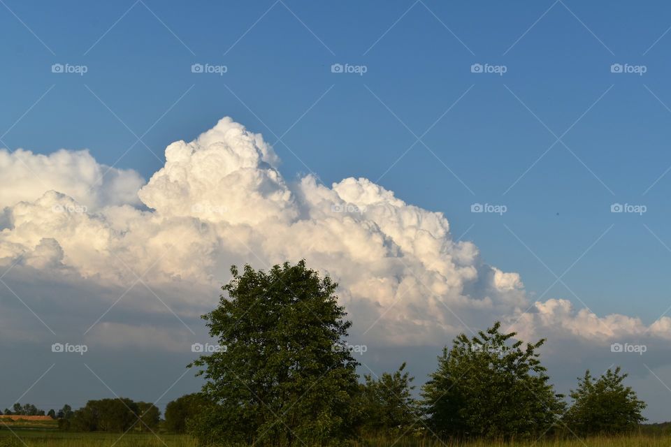 Snow-white clouds in the shape of mountains on a background of blue sky