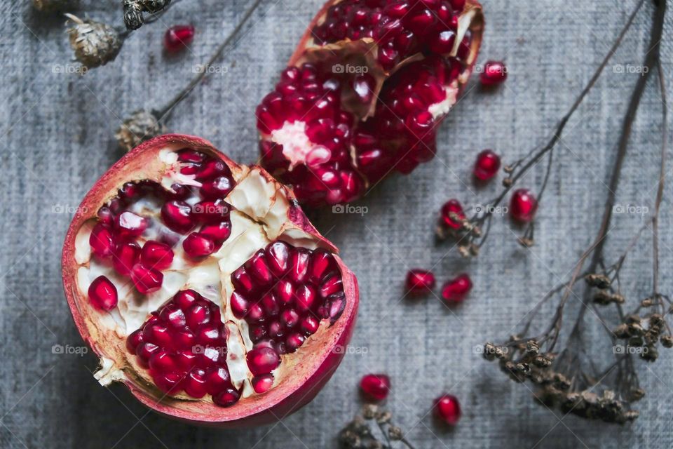 Flat lay with cut magenta pomegranate on a gray cloth