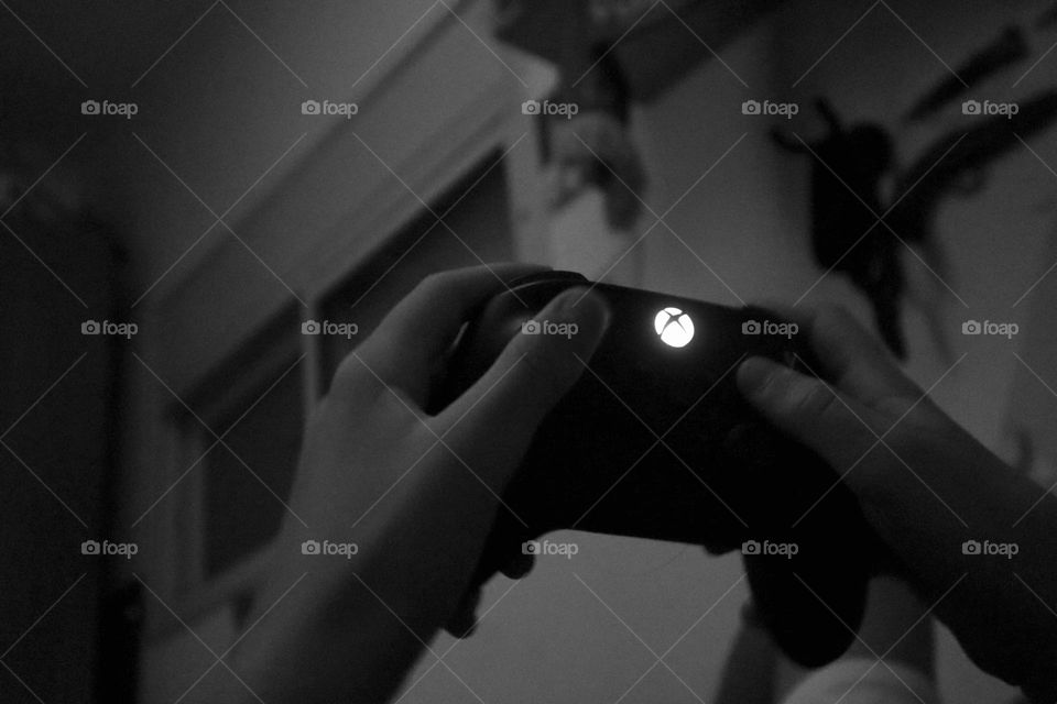 Xbox controller holds by kid hand’s playing video games B&W