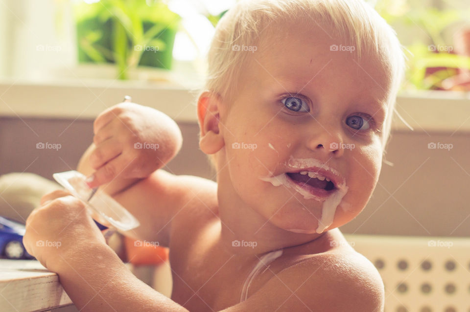 little boy is eating yogurt messily