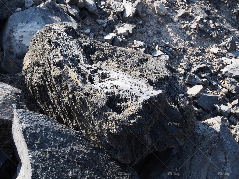 Textured Obsidian and hardened lava rock on a sunny fall day at the Big Obsidian Flow in the Newberry National Volcanic Monument in Central Oregon.