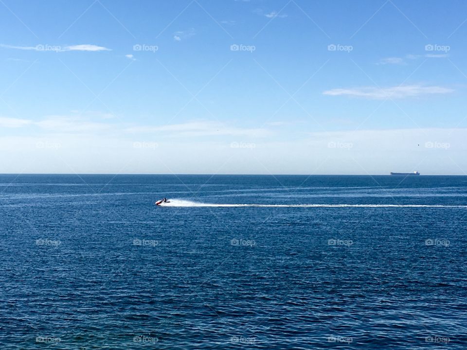 Sea Doo on the ocean with a cargo ship in the distance 