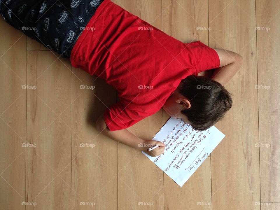 Elevated view of a boy writing text on paper with pen