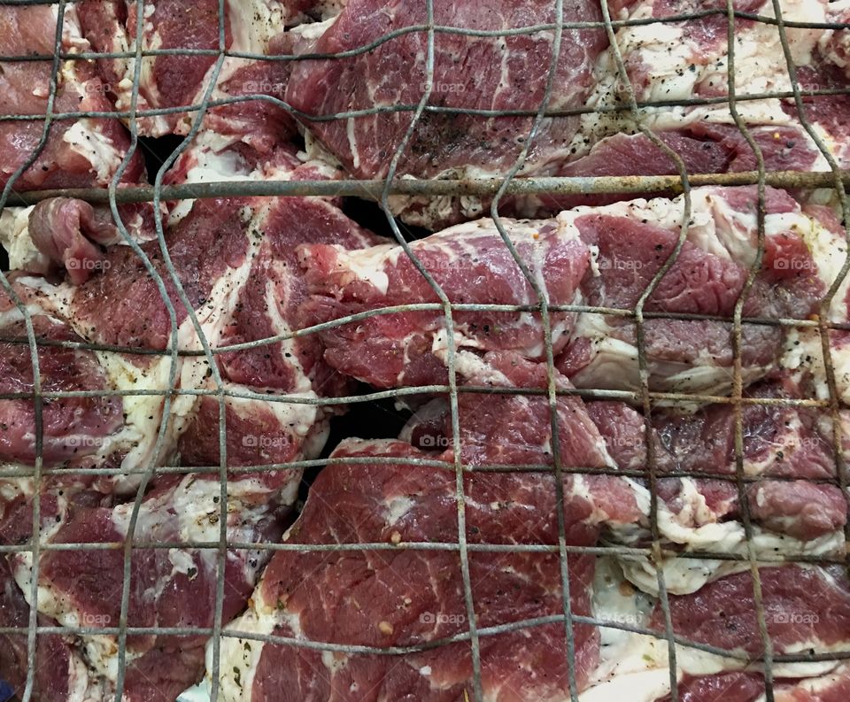 marinated pieces of pork meat on the grill to grill, full frame