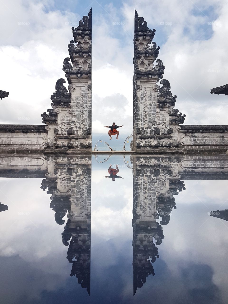 High jump over Heaven's door, performed wearing the traditional Sarong!  Lempuyang temple, Bali, Indonesia. Reaching this place on a volcanic mountain is an adventure itself!