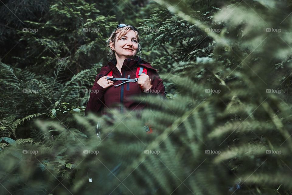 Woman with backpack hiking in forest, actively spending summer vacation close to nature. Woman walking on path among trees