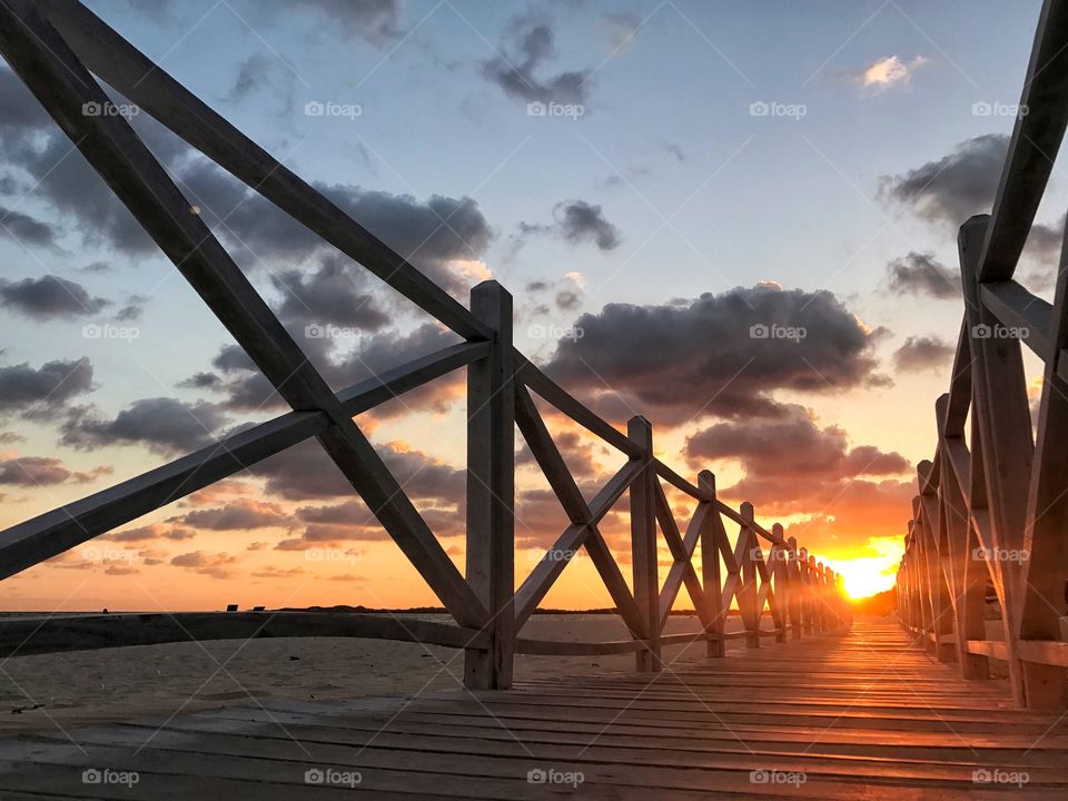 Wooden bridge over sea during sunset