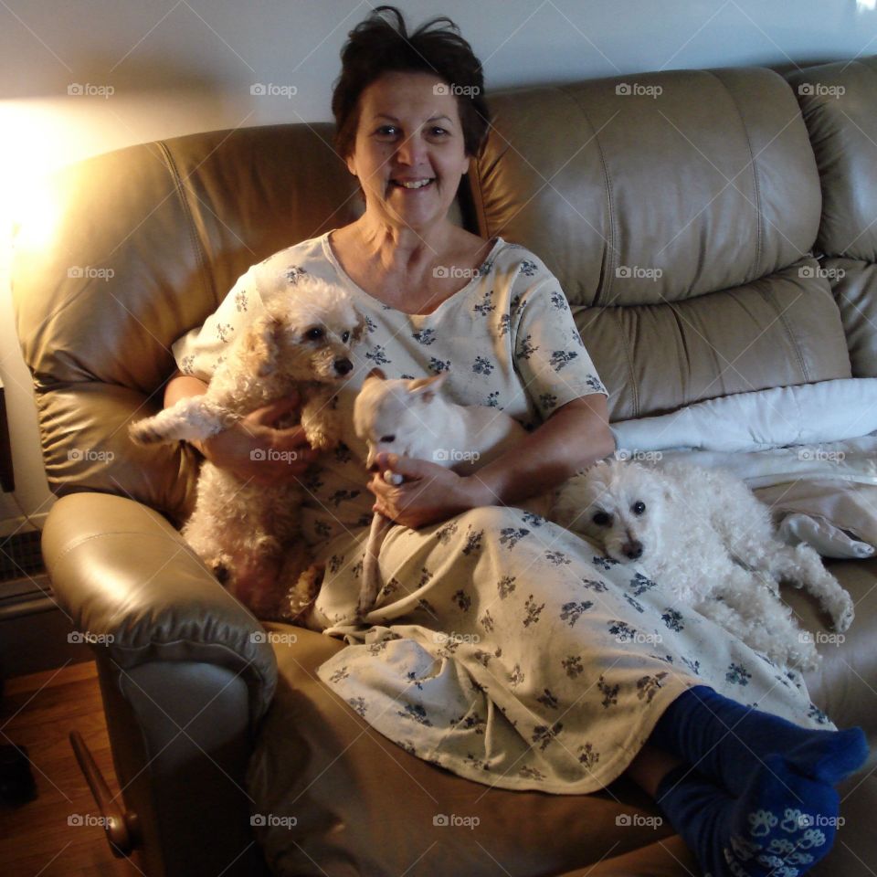 Mature woman with puppies sitting on sofa