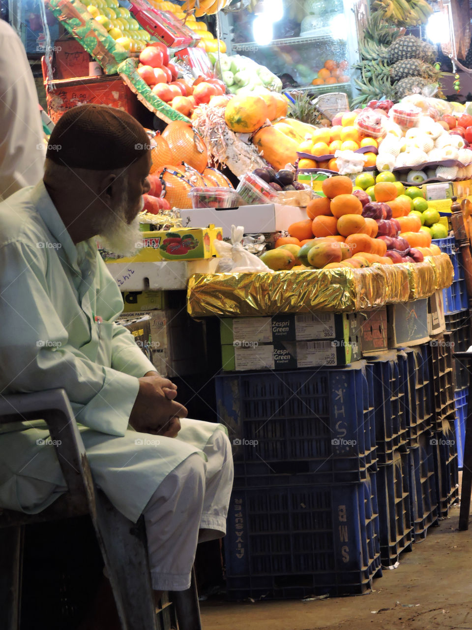 An old man sitting idle in his little fruit shop