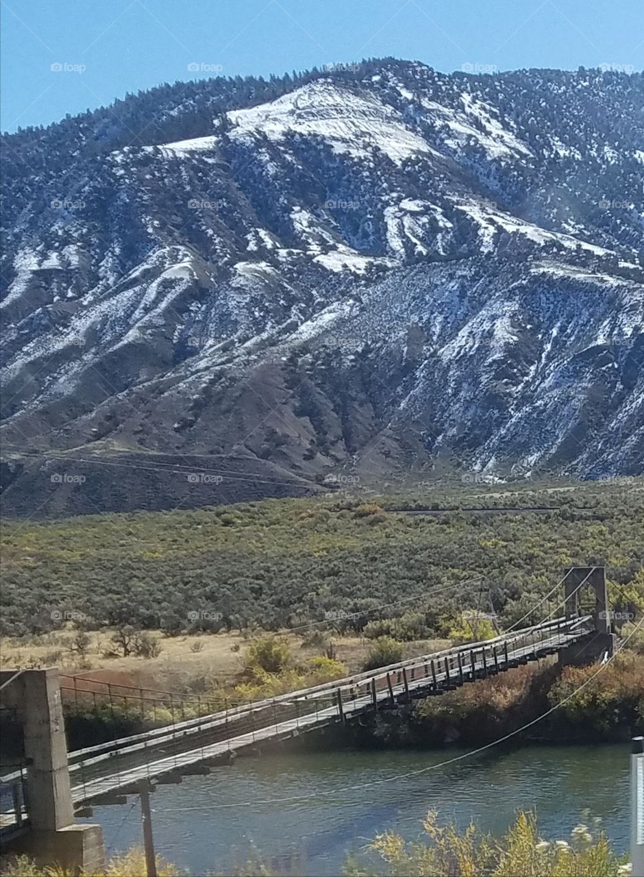 Bridge going over spring water looking upon beautiful Colorado mountains