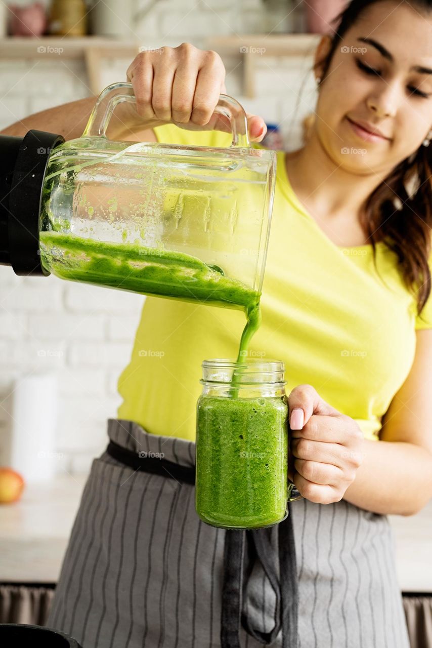 woman pouring green smoothie