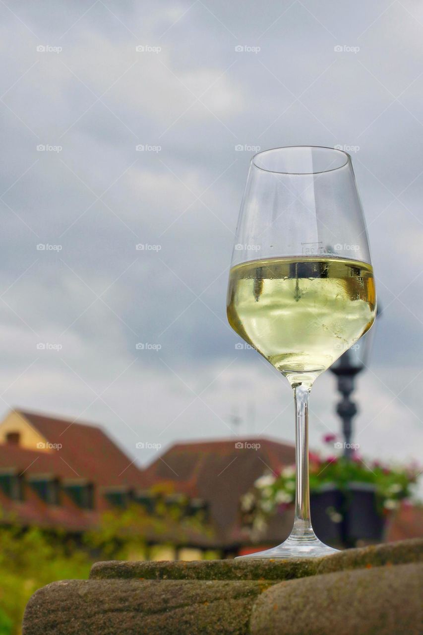 A glass of white wine on a stone in front of a city