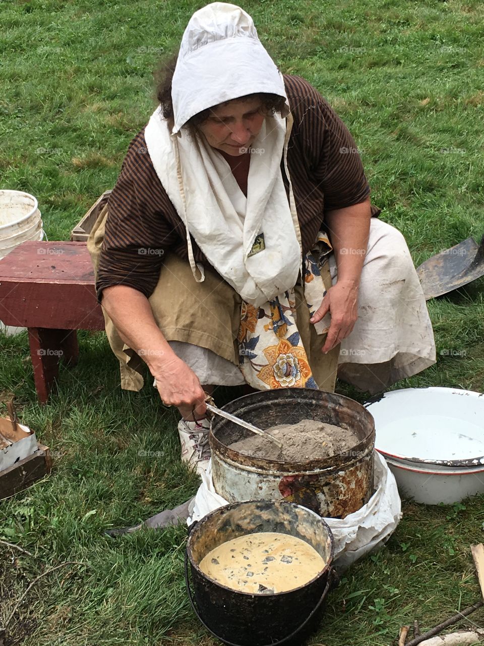 A volunteer demonstrating the process of mixing ash with triglycerides in a colonial practice for making soap. 