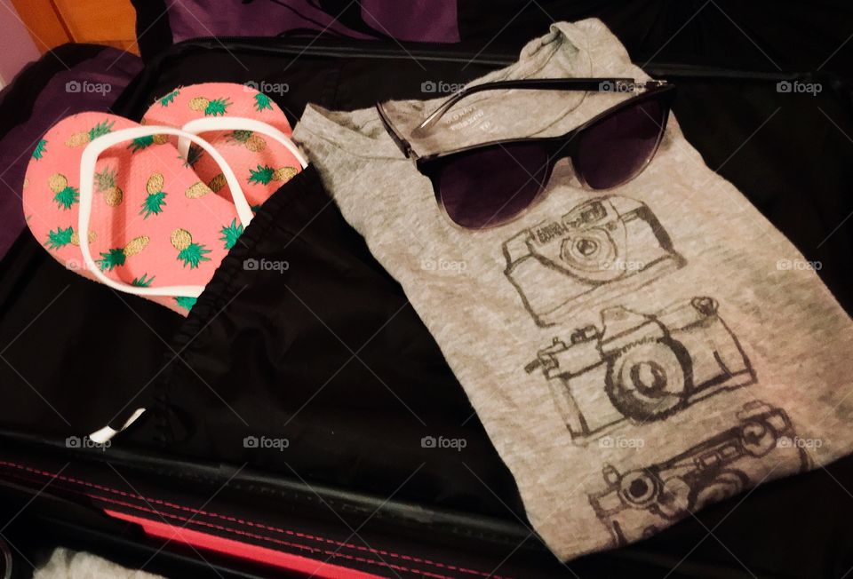 My suitcase: camera t-shirt, sunglasses, and pink pineapple flip flops