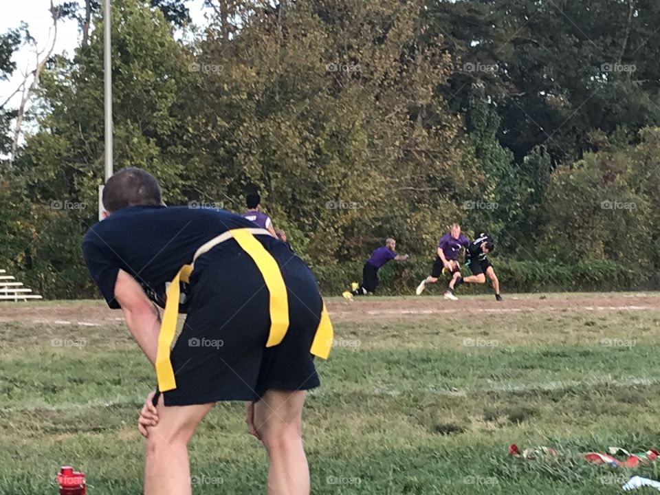 Flag football player bent in the foreground as the action takes place