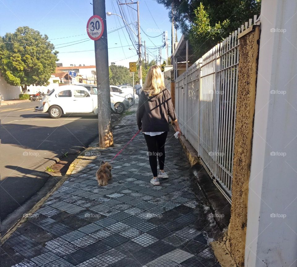 A lady walking her small dog in the morning