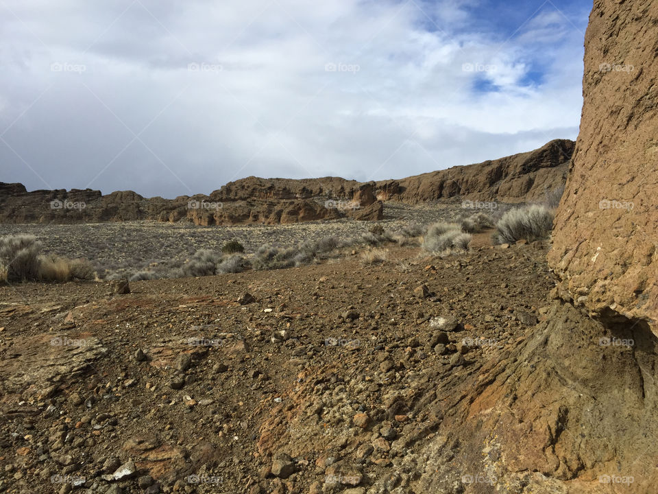The inside ground of the magnificent Fort Rock with blue sky peaking through the clouds. 