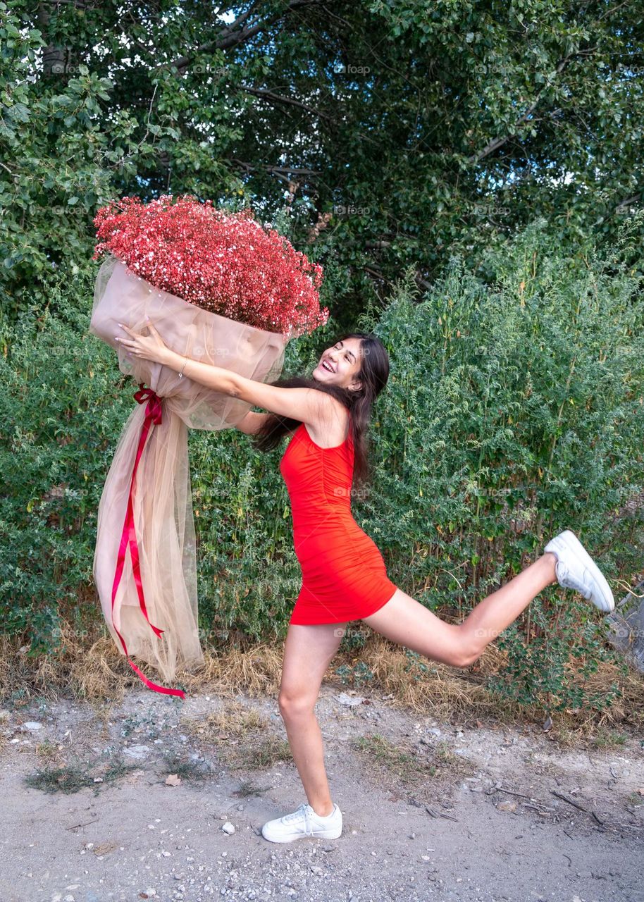 Beautiful Girl Dances with a Large Bouquet of Red Flowers