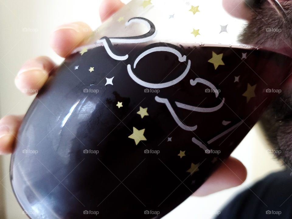 A man drinking sparkling red wine in wine tumbler to welcome a new year 2021