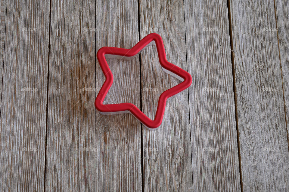 Cookie cutter in shape of a star on wood background