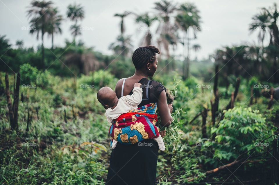 a woman carrying her baby in her back to the farm