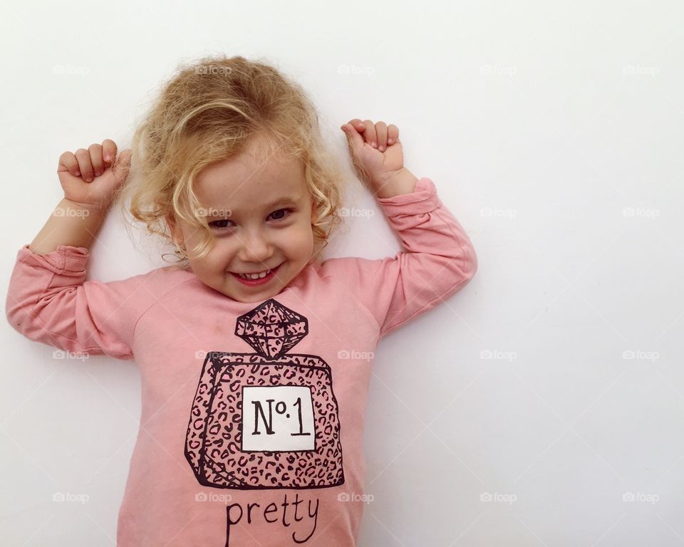 A little girl smiling against white background