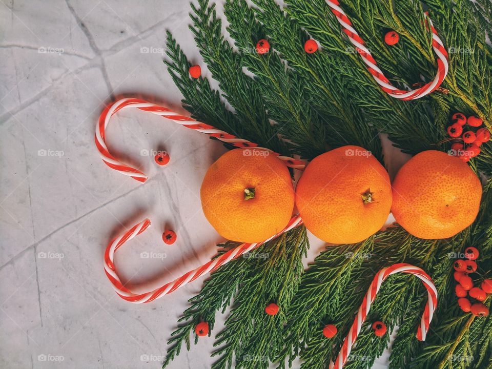 Christmas and New Year background with spruce branch, candies, decorations and tangerines Flat lay. Top view.