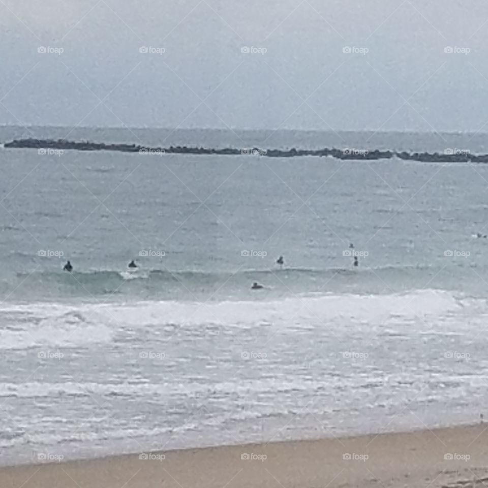 People swimming out to surf in NC in May 2018
