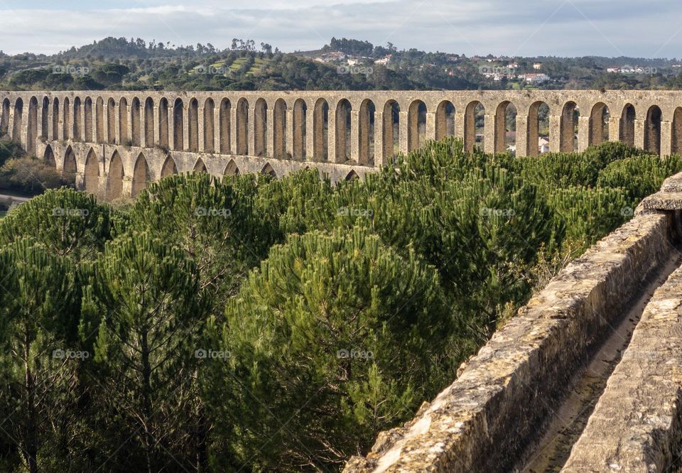 The arches of Pegões Aqueduct spread across in landscape in Tomar, Portugal